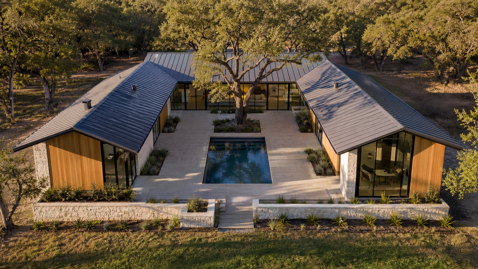 Aerial view of a U-shaped modern courtyard home with a central reflecting pool and live oak