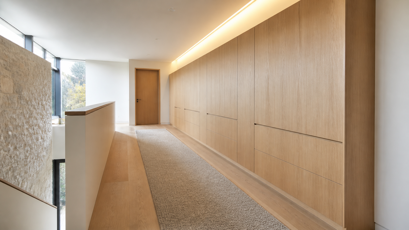 Wide carpeted upstairs hallway with millwork acting as an acoustic buffer between bedrooms