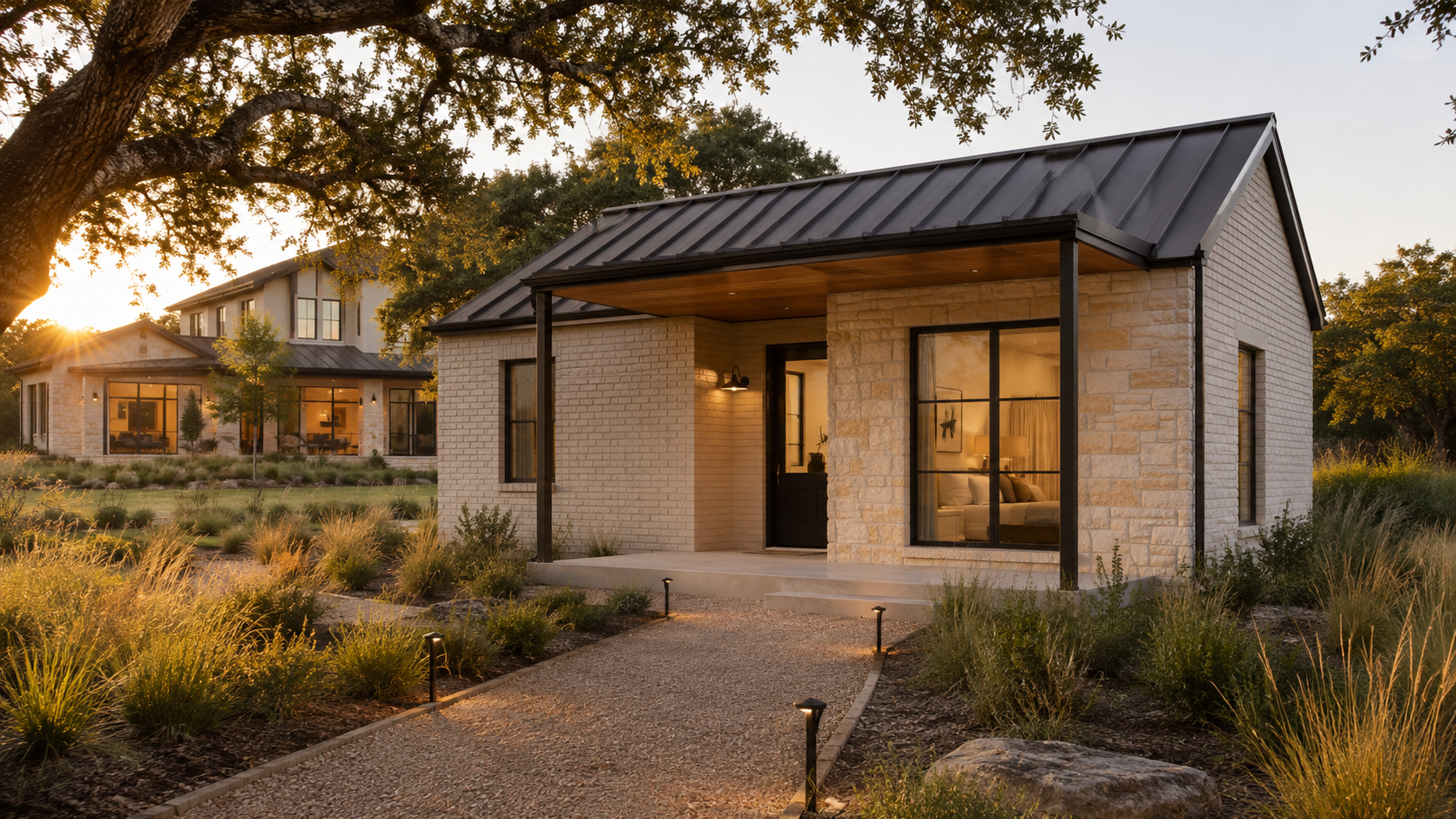 Detached guest casita with a metal roof and stone exterior behind a custom home at golden hour