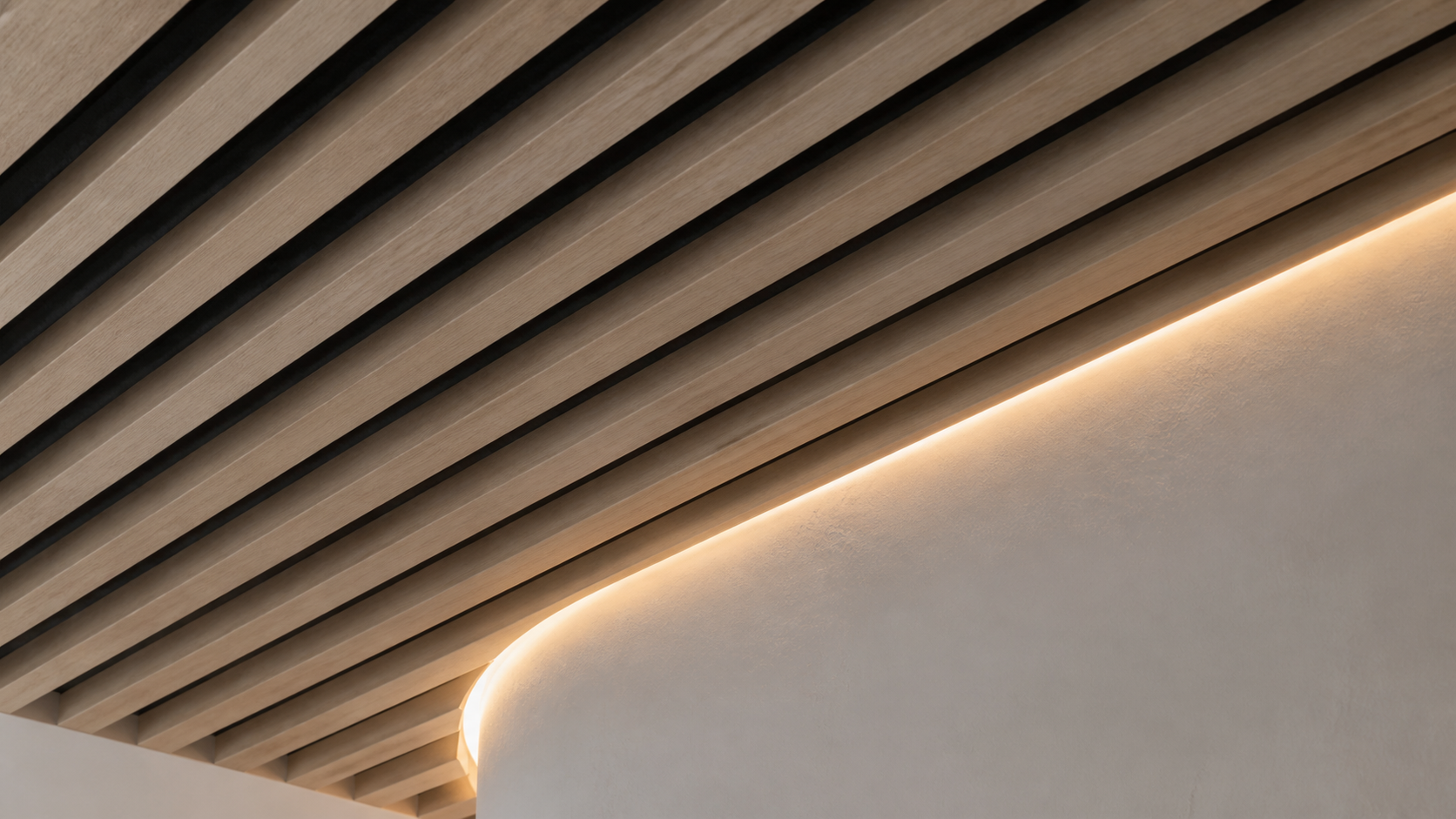 White oak slat ceiling meeting a curved plaster cove with concealed lighting