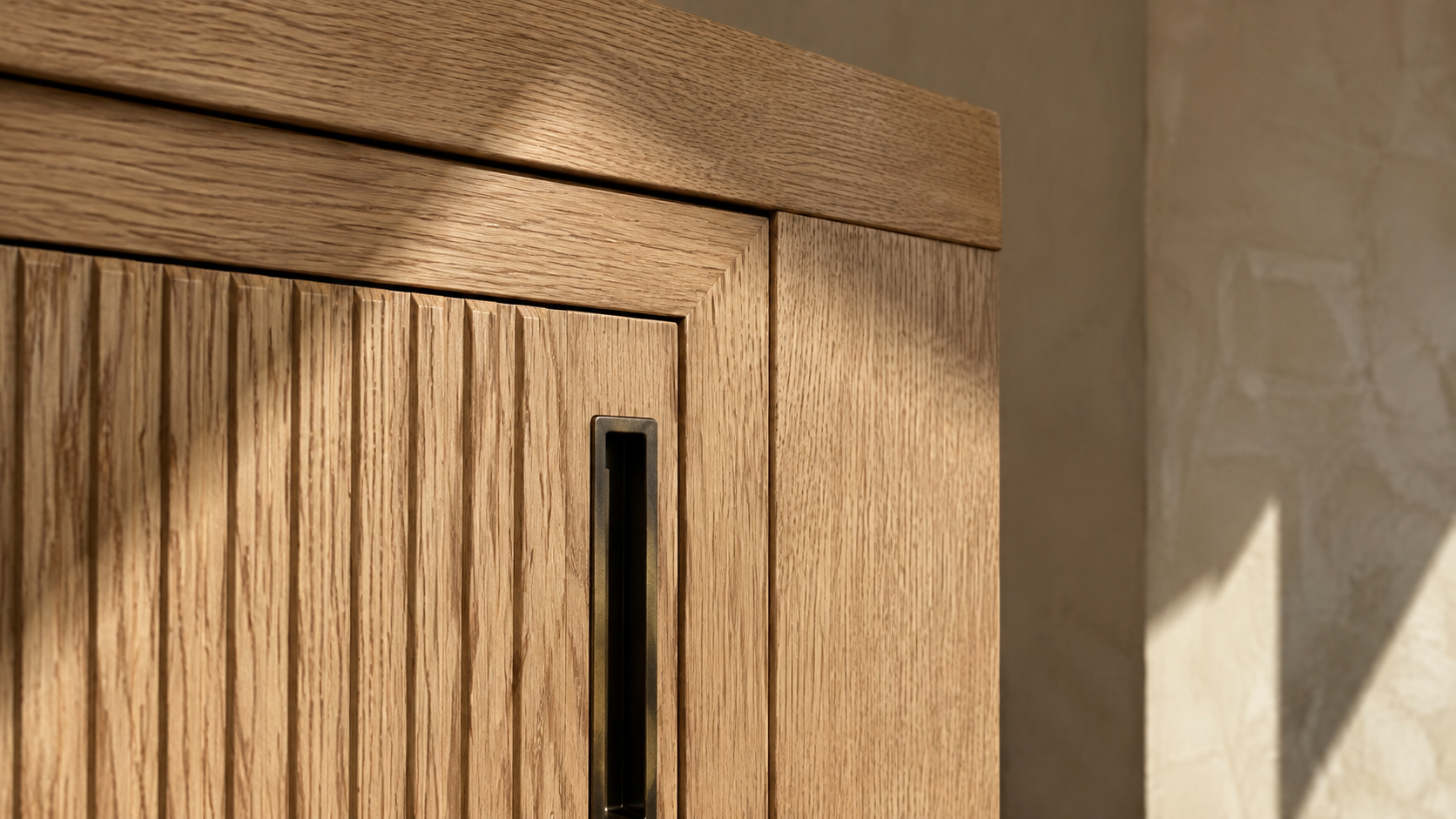 Close-up of a flush inset white oak cabinet door with a narrow reveal and bronze pull