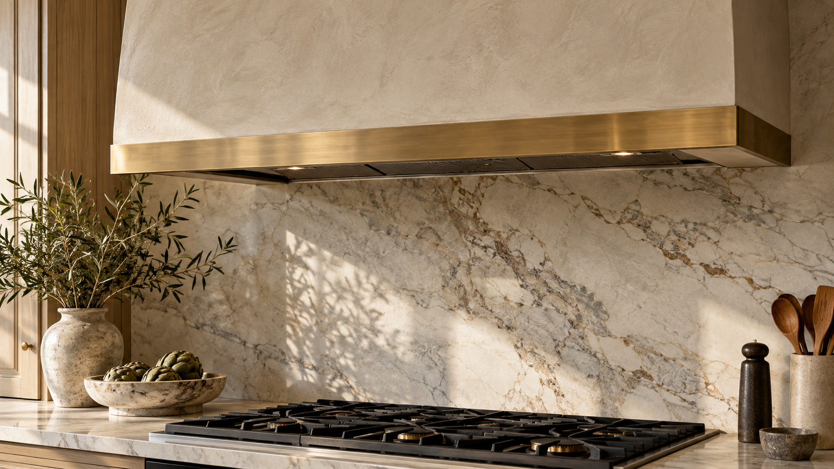 Limewash plaster range hood surround with brass trim band above a cooktop