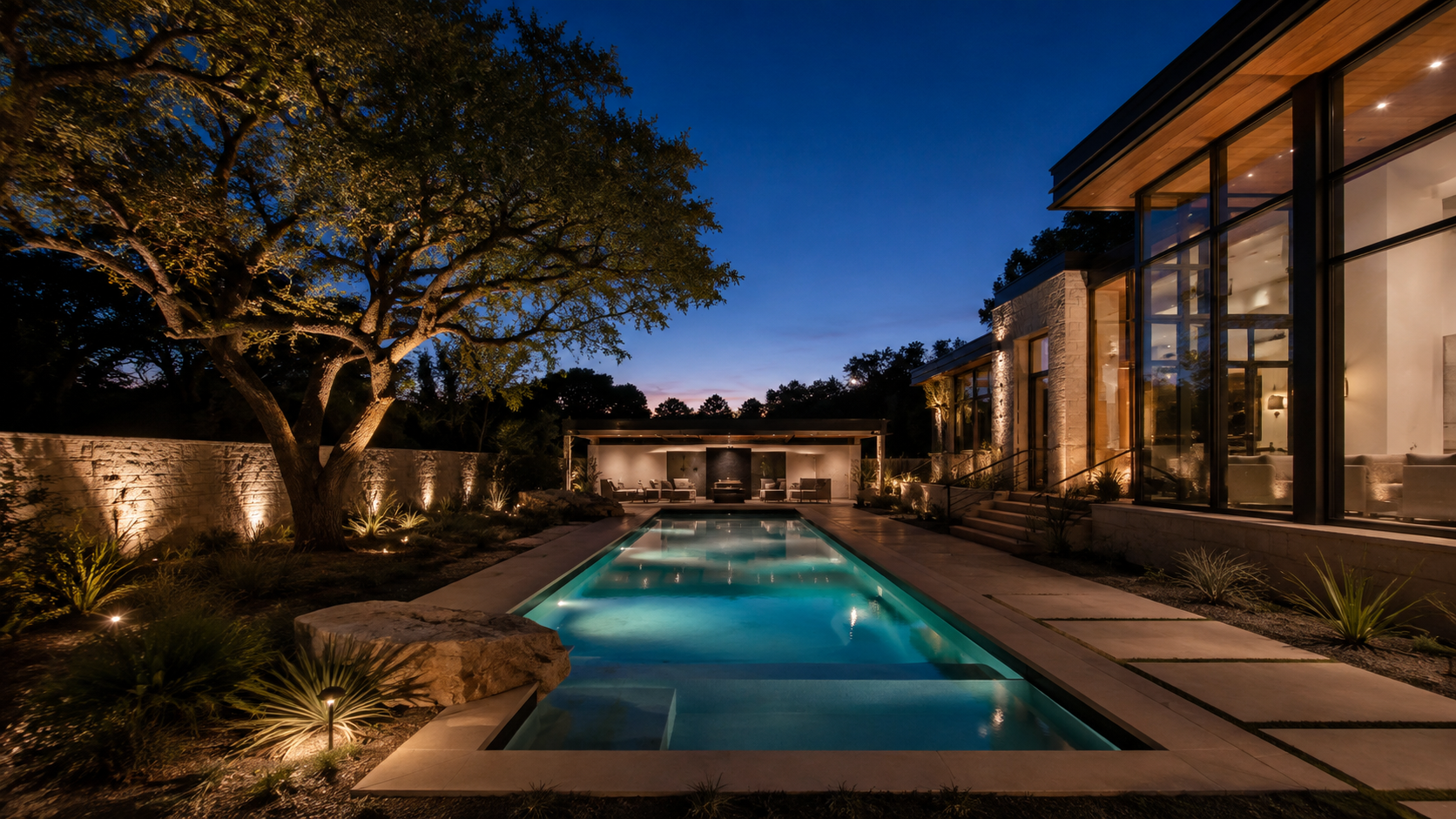 Pool and backyard at dusk with balanced landscape and interior lighting
